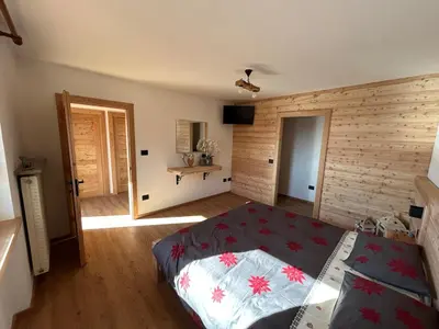 a bedroom with a bed and a wooden wall at La Casa del Zio Bepi in Bedollo