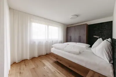 a bedroom with a bed with white sheets and a window at Baumannhof in Sarntal