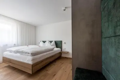 a bedroom with a large white bed and wooden floors at Baumannhof in Sarntal