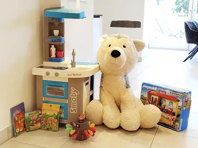 a teddy bear sitting on the floor next to books at Panorama-Designapartment mit Kamin, Terrasse & Bergblick Nähe Sterzing - Villa Tribulaunblick in Colle Isarco