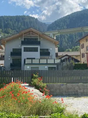 a house with a fence and flowers in front of it at Panorama-Designapartment mit Kamin, Terrasse & Bergblick Nähe Sterzing - Villa Tribulaunblick in Colle Isarco