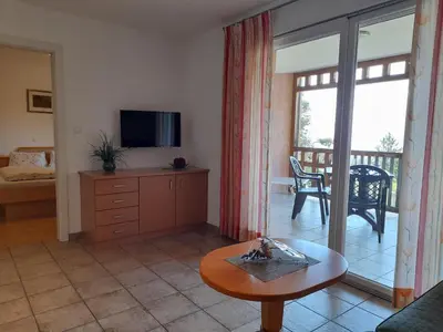 a living room with a television and a table at Apartmenthaus am Waalweg in Caines