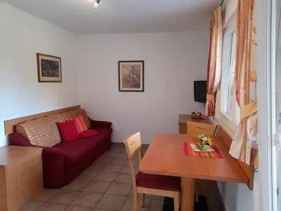 a living room with a red couch and a table at Apartmenthaus am Waalweg in Caines