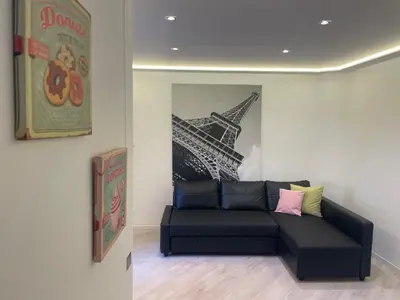 a couch in a room with a picture of the eiffel tower at Casa Tilì in Ziano di Fiemme