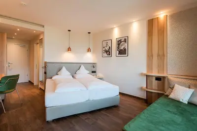 a bedroom with a white bed and a green table at Alpenpalais Kröll in Schenna