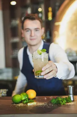 a man in a kitchen holding a drink at Alpenpalais Kröll in Schenna
