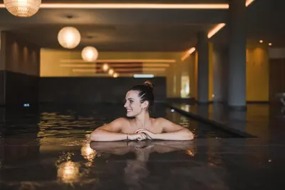 a woman laying in a swimming pool at Alpenpalais Kröll in Schenna