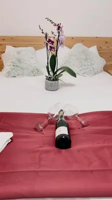 a pair of glasses and a vase with flowers on a bed at Appartment Alleghe center in Alleghe