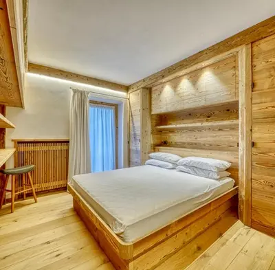 a bedroom with a large bed with a wooden wall at Luxury apartment in Cortina in Cortina dʼAmpezzo