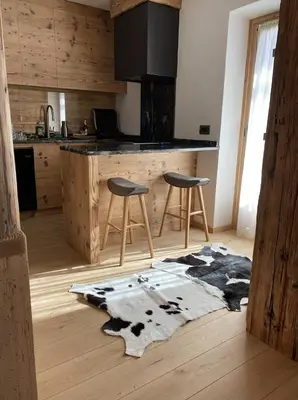 a kitchen with a counter and two stools and a rug at Luxury apartment in Cortina in Cortina dʼAmpezzo