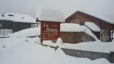 a sign in the snow in front of a building at La Majon Apartments in Selva di Val Gardena