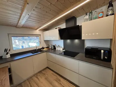 a kitchen with white cabinets and a black counter top at Appartamento Cima 12 in Pozza di Fassa