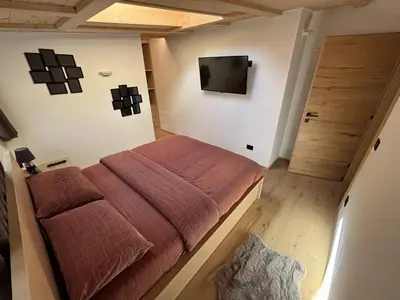 a bedroom with a bed and a television on the wall at Appartamento Cima 12 in Pozza di Fassa