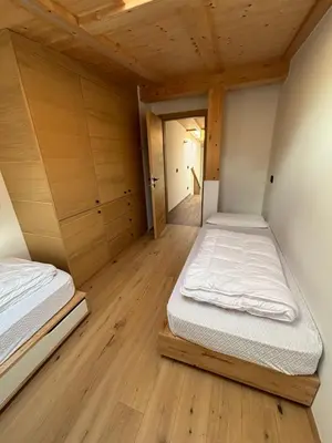 two beds in a room with wooden floors at Appartamento Cima 12 in Pozza di Fassa