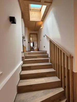 a hallway with wooden stairs with a skylight at Appartamento Cima 12 in Pozza di Fassa