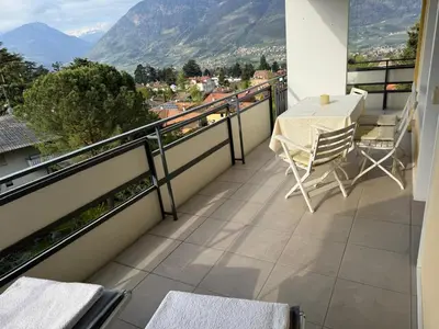 a balcony with a table and chairs and mountains at MERANEA- sonnig - ruhig - elegant - ideal zum länger bleiben - Glasfaser in Merano