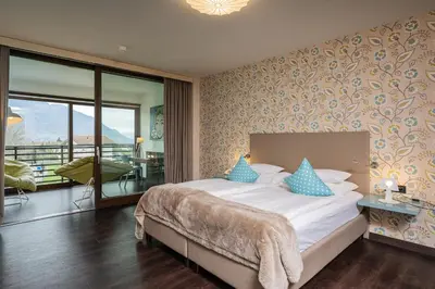 a bedroom with a large bed and a balcony at Hotel Gartner in Tirolo