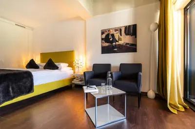 a hotel room with a bed and two chairs and a table at Hotel Gartner in Tirolo