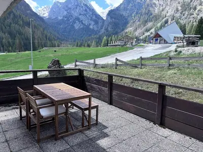 a table and chair on a balcony with a view of a mountain at Marmolada Escape in Malga Ciapela