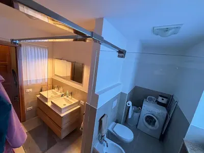 a bathroom with a toilet and a sink and a washing machine at Marmolada Escape in Malga Ciapela