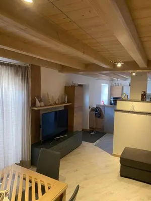 a living room with a flat screen tv and a kitchen at tabià piz meda in Moena