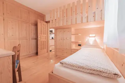 a small bedroom with wooden cabinets and a bed at Ladin Apartment in Antermoia