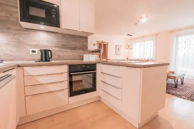 a kitchen with white cabinets and a microwave at Ladin Apartment in Antermoia