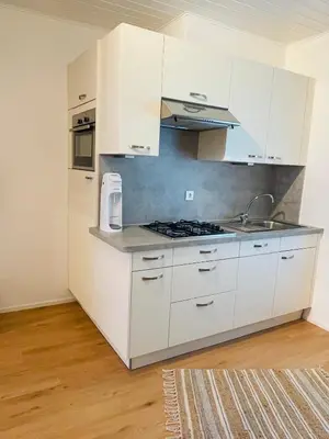 a white kitchen with white cabinets and a sink at Wiesenheim- Schlernblick in Penone