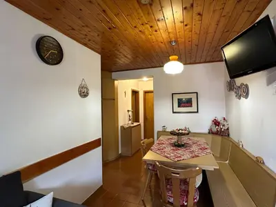 a dining room with a table and a tv at Mansarda nelle dolomiti in Falcade