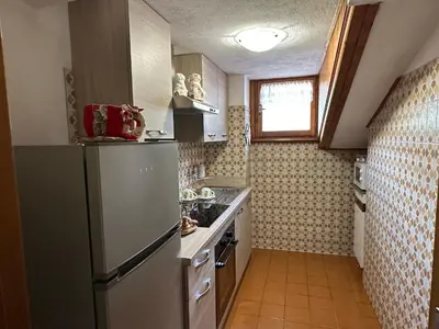 a kitchen with a refrigerator and a sink at Mansarda nelle dolomiti in Falcade