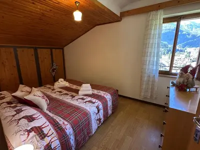 a bedroom with two beds and a window at Mansarda nelle dolomiti in Falcade