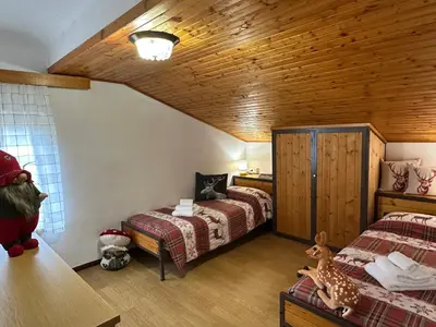 a bedroom with two beds and a wooden ceiling at Mansarda nelle dolomiti in Falcade