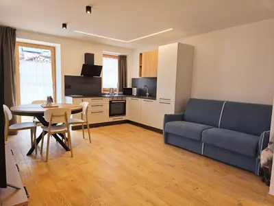 a living room with a blue couch and a table at Alpine Lodge Tesero - Alpine Stay Apartments in Tesero