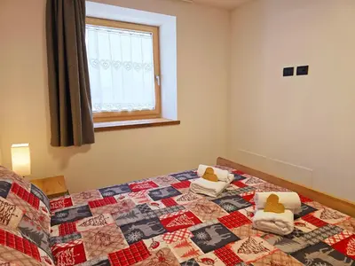 a bedroom with a bed with a quilt on it at Alpine Lodge Tesero - Alpine Stay Apartments in Tesero