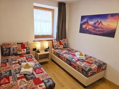 a bedroom with two beds and a window at Alpine Lodge Tesero - Alpine Stay Apartments in Tesero
