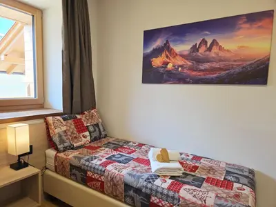 a bedroom with a bed and a painting on the wall at Alpine Lodge Tesero - Alpine Stay Apartments in Tesero