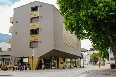 a building on a street with a tree at Rooftop Apartment - Alpstay in Naturno