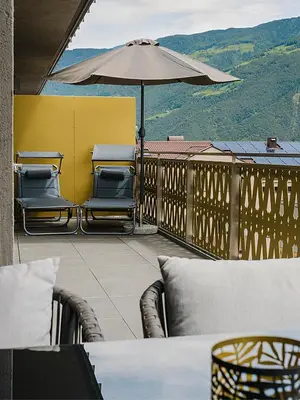 a patio with chairs and an umbrella on a balcony at Rooftop Apartment - Alpstay in Naturno