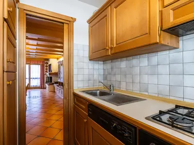 a kitchen with wooden cabinets and a sink at Apartment Corte dei Larici by Interhome in Campitello di Fassa
