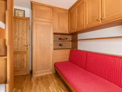 a red bench in a room with wooden cabinets at Apartment Corte dei Larici by Interhome in Campitello di Fassa