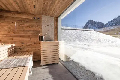a room with a balcony with a view of the mountains at Brunelle Seiser Alm Lodge in Alpe di Siusi