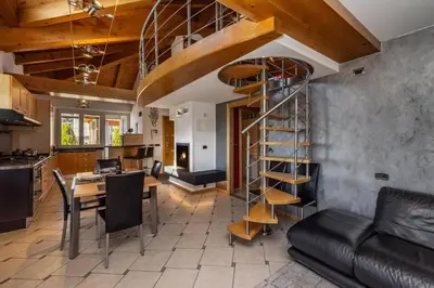 a kitchen and a living room with a spiral staircase at Villa Azzurra, Cloz Ospitar in Cloz