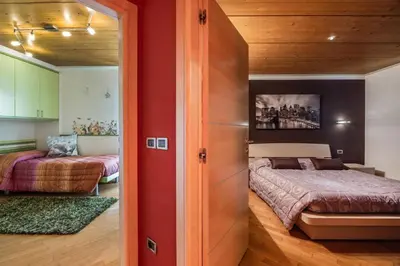 a bedroom with two beds and a red wall at Villa Azzurra, Cloz Ospitar in Cloz