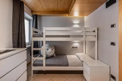 a bunk bed in a small room with a ladder at Villa Azzurra, Cloz Ospitar in Cloz