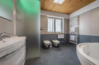 a bathroom with two toilets and a sink and a tub at Villa Azzurra, Cloz Ospitar in Cloz