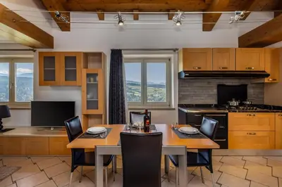 a kitchen with wooden cabinets and tables and chairs at Villa Azzurra, Cloz Ospitar in Cloz