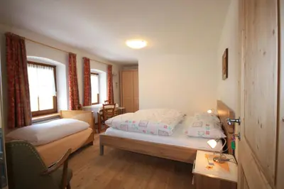 a bedroom with two beds and a table with a lamp at Haus Schmiedhofer in Villabassa