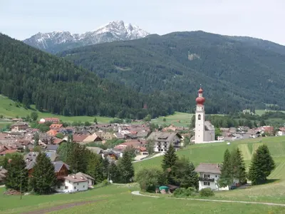 a small village with a church and mountains in the background at Haus Schmiedhofer in Villabassa