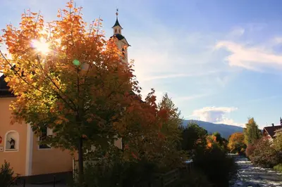 a church with a tower with a tree in front of it at Haus Schmiedhofer in Villabassa