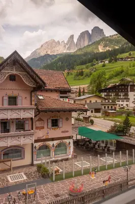 a building in a town with mountains in the background at Lovely,cosy Apartment 2 Min Skilift Walk in Campitello di Fassa